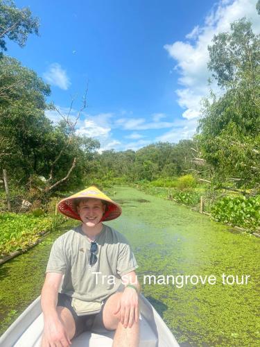 a man wearing a hat in a boat on a river at Song Ngư Riverside Homestay in Can Tho