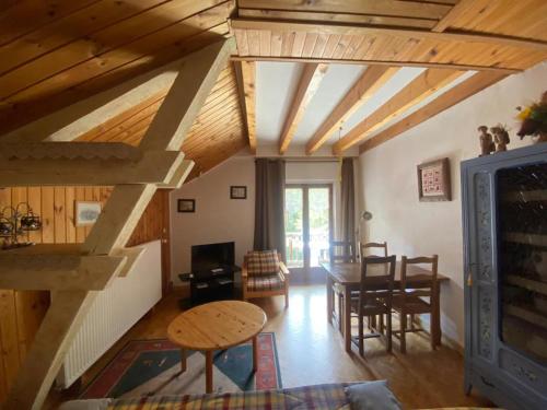 sala de estar con techos de madera, mesa y sillas en Chez Zoë au Chalet de segure, en Ristolas