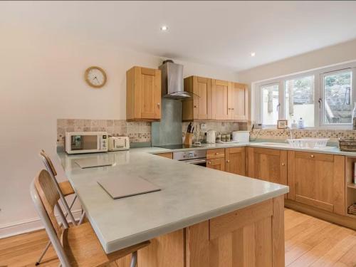 a kitchen with wooden cabinets and a large counter top at Clotted Cream Cottage: Countryside calm: Close to beach: Dartmouth: Devon in Dartmouth