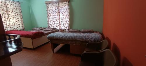 Habitación con 2 camas y una silla. en Akash Homestay en Shimla