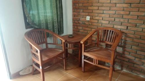 マゲランにあるHomestay Pelangiの木製の椅子2脚、テーブル1台、レンガの壁