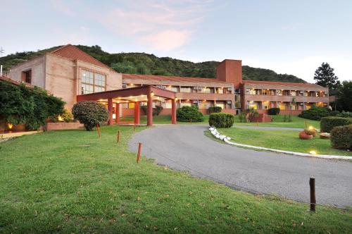 a large building with a road in front of it at Pinares del Cerro Resort & Suites in Villa Carlos Paz