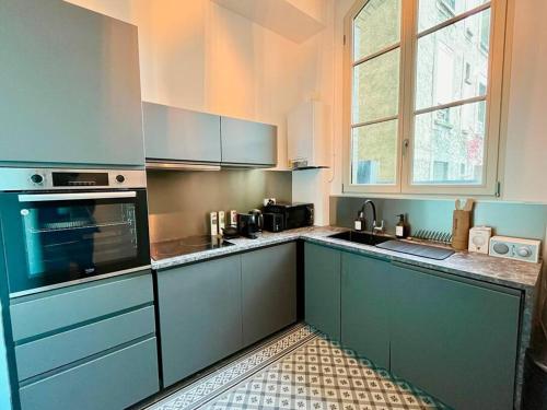 una cucina con mobili blu e un forno a piano cottura di Champagne des Anges - Proche Cathédrale de Reims a Reims