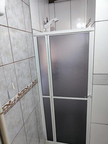 La salle de bains est pourvue d'une douche avec une porte en verre. dans l'établissement Casas do juju, à Palhoça