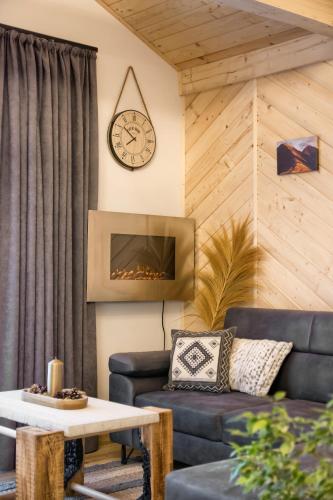 a living room with a couch and a clock on the wall at Domek Leśny in Zakopane