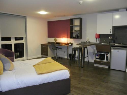 a bedroom with a large bed and a kitchen with a table at Modern Stylish Apartments and Rooms at Student Roost Corner House in Sheffield in Sheffield