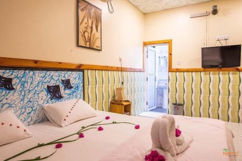 a bedroom with a bed and a tv on the wall at Summer Vibes Beach Front in Rasdu
