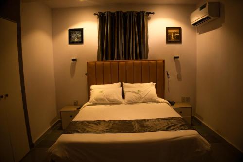 a bedroom with a bed with white sheets and pillows at Klulead Garden and Suites in Ijebu Ode