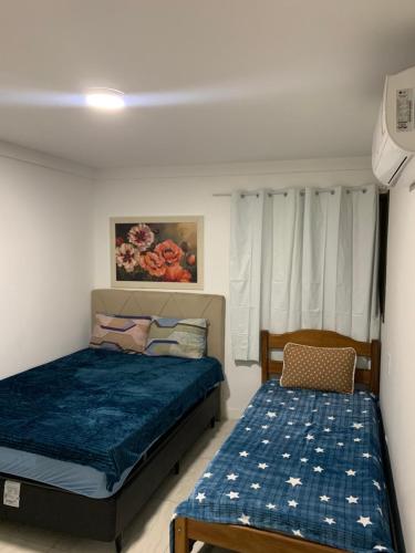 a bedroom with two beds and a chair at apartamento de frente para o mar com linda area de lazer in Arraial do Cabo