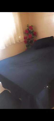 um quarto com uma cama e um vaso com flores vermelhas em Olympios House no Rio de Janeiro