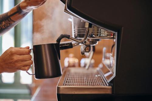 メデジンにあるAntipoda Hotel Boutiqueの人がコーヒーマシンの前でコーヒーカップを持っている