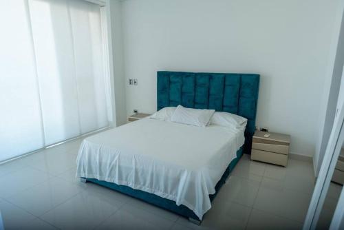 バランキージャにあるLux Duplex, unique views,Villa Santosの白いベッド(青いヘッドボード付)が備わるベッドルームです。