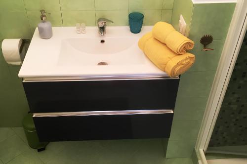 La salle de bains est pourvue d'un lavabo et de serviettes jaunes. dans l'établissement Alloggio Turistico via dei Faggi - Room, à Rome