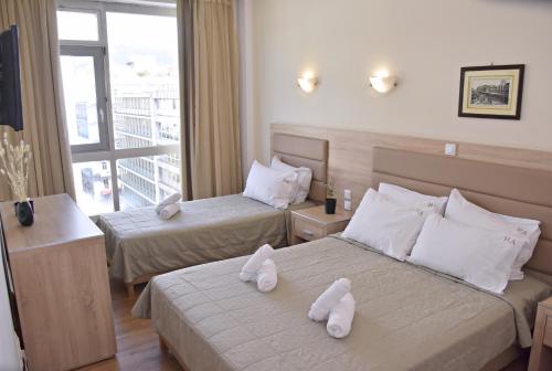 two beds in a hotel room with towels on them at Arethusa Hotel in Athens