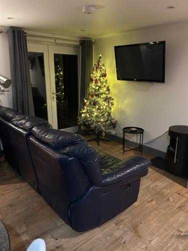 a living room with a christmas tree and a leather couch at Beach hut seaside cottage in Sheringham