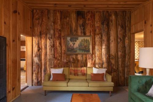 ein Wohnzimmer mit einem Sofa an einer Holzwand in der Unterkunft 2407 - Oak Knoll #9 cabin in Big Bear Lake