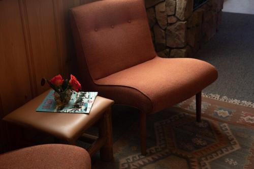 a brown chair and a table with a vase of flowers at 2412 - Oak Knoll Studio with Jacuzzi #15 cabin in Big Bear Lake