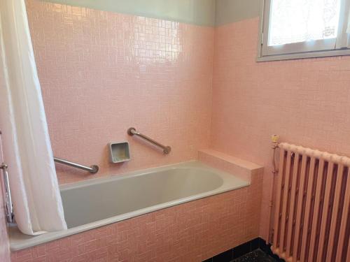 eine Badewanne im rosa Badezimmer mit Fenster in der Unterkunft 住在巴黎 in Bondy