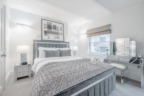 a white bedroom with a large bed and a window at Tottenham Court's House - 2 Bed in London