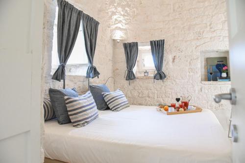 een slaapkamer met een groot wit bed met blauwe kussens bij Trulli Terrarossa con Piscina in Martina Franca