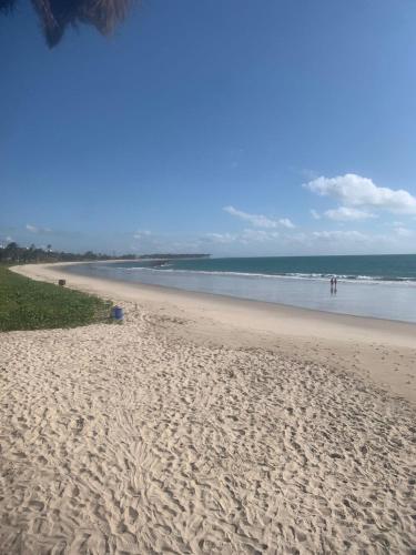a sandy beach with people walking in the ocean at Tamandaré Praia Hotel in Tamandaré