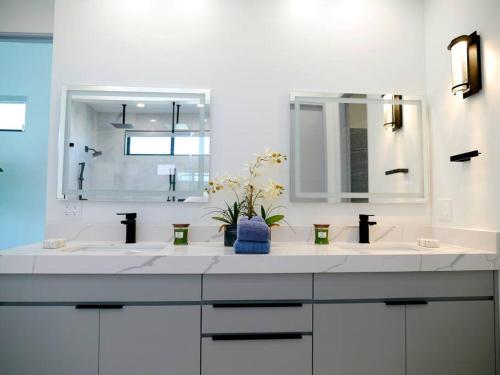 een witte badkamer met 2 wastafels en een spiegel bij OC Oasis Beach Pad in Huntington Beach