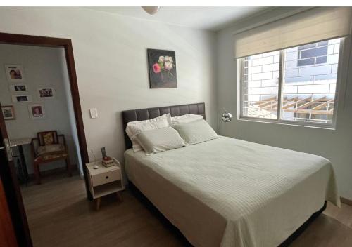 1 dormitorio con 1 cama blanca y ventana en Casa ótima localização, en Curitiba