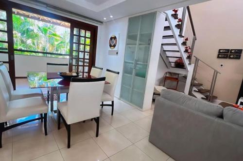 a living room with a table and a staircase at Apartamento duplex em Praia do Forte - 2 suítes in Praia do Forte