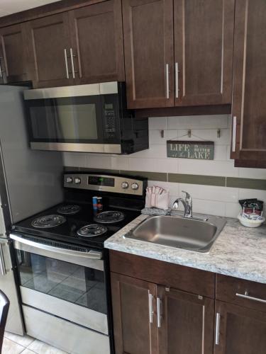 a kitchen with a sink and a stove and a microwave at Safari Beach Resort in Osoyoos