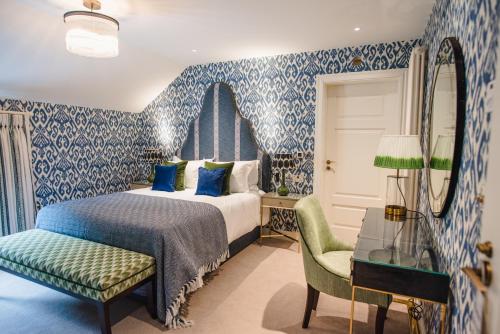 a blue and white bedroom with a bed and a chair at Dewars Restaurant and Rooms in Malton