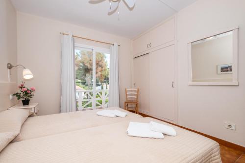 a white bedroom with two beds and a window at apartamento edificio migjorn santo tomas in Santo Tomás