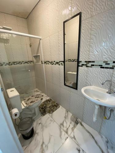 uma casa de banho com um WC, um lavatório e um espelho. em pousada fast sleep no Guarujá