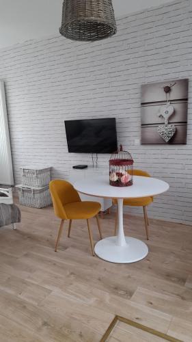 un salon avec une table et des chaises blanches dans l'établissement Gîte location meublée Aumale - studio en centre-ville - La maison en brique, à Aumale