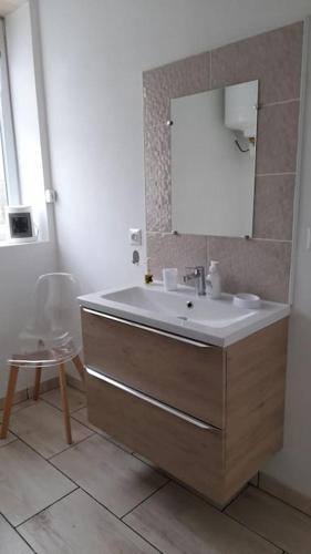 une salle de bain avec un lavabo, un miroir et une chaise dans l'établissement Gîte location meublée Aumale - studio en centre-ville - La maison en brique, à Aumale