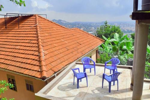drie blauwe stoelen op een patio met een oranje dak bij Makindye Kizungu Holiday Villa in Makindye