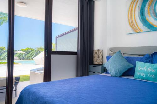 een slaapkamer met een blauw bed en een groot raam bij Apartment with private jacuzzi and King bed Near Hard Rock hotel & casino in Punta Cana