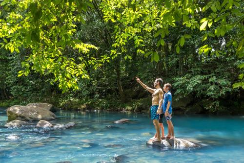 two people standing on a rock in a river at Hideaway Rio Celeste Hotel in Bijagua