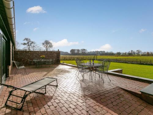 a patio with a table and chairs and a field at De Hoeve II in Hulsel