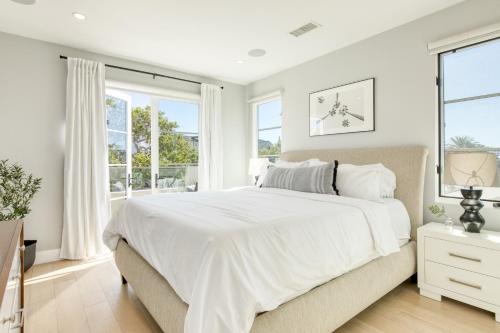 1 dormitorio blanco con 1 cama grande y ventanas en Sea Crown by AvantStay 5mins from the Beach w Multiple Terraces PermitSLP13639, en Newport Beach