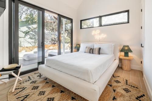 a bedroom with a white bed and large windows at Henley by AvantStay Plunge Pool Incredible Patio Guest House in Austin