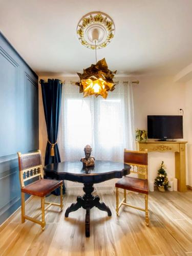 une salle à manger avec une table, des chaises et un lustre dans l'établissement L'OSMOSE avec balcon, 3mn place centrale Château, à Saverne