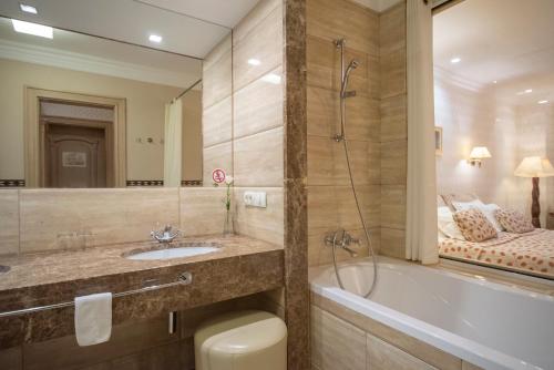 een badkamer met een bad, een wastafel en een bad bij Swiss Hotel in Lviv