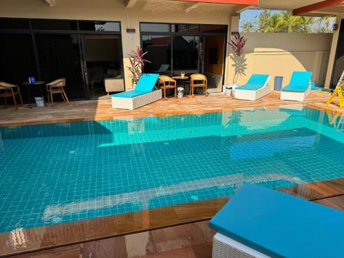 a swimming pool with blue chairs and a table at S & D Guesthouse in Kampot