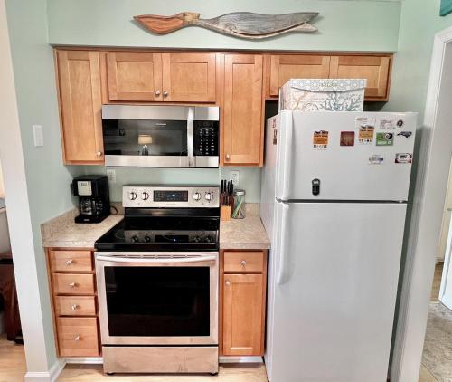 a kitchen with white appliances and wooden cabinets at Just Another Day in Paradise in Manteo