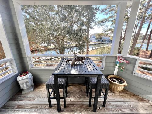 a screened porch with a table and chairs on it at Just Another Day in Paradise in Manteo