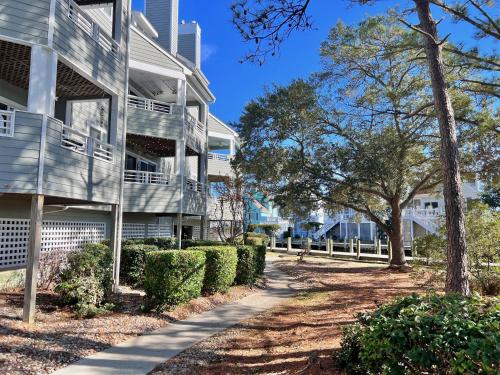 a sidewalk next to a building with bushes and trees at Just Another Day in Paradise in Manteo