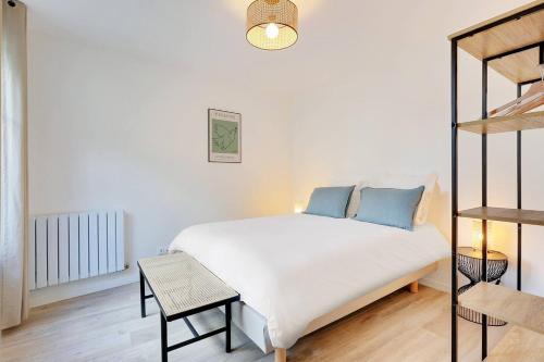 een wit bed met blauwe kussens in een kamer bij La Résidence Alpha Viroflay 301 - Duplex 2 chambres - 6 pers in Viroflay