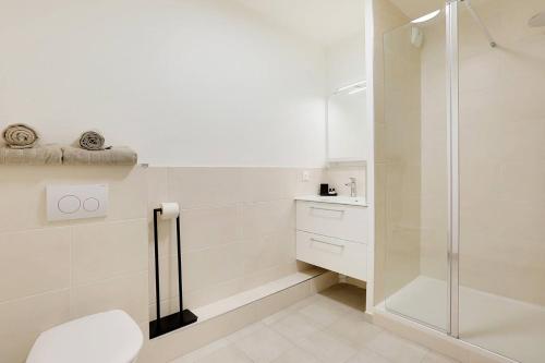 a white bathroom with a shower and a toilet at La Résidence Alpha Viroflay 301 - Duplex 2 chambres - 6 pers in Viroflay