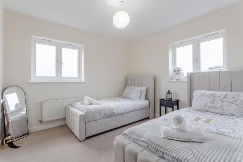 a white bedroom with two beds and a mirror at Premium Nights - Harry Potter, Professional, Family stay in Watford