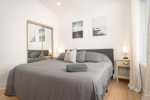 een witte slaapkamer met een groot bed en een spiegel bij Contemporary renovated house in southshore MTL in Brossard
